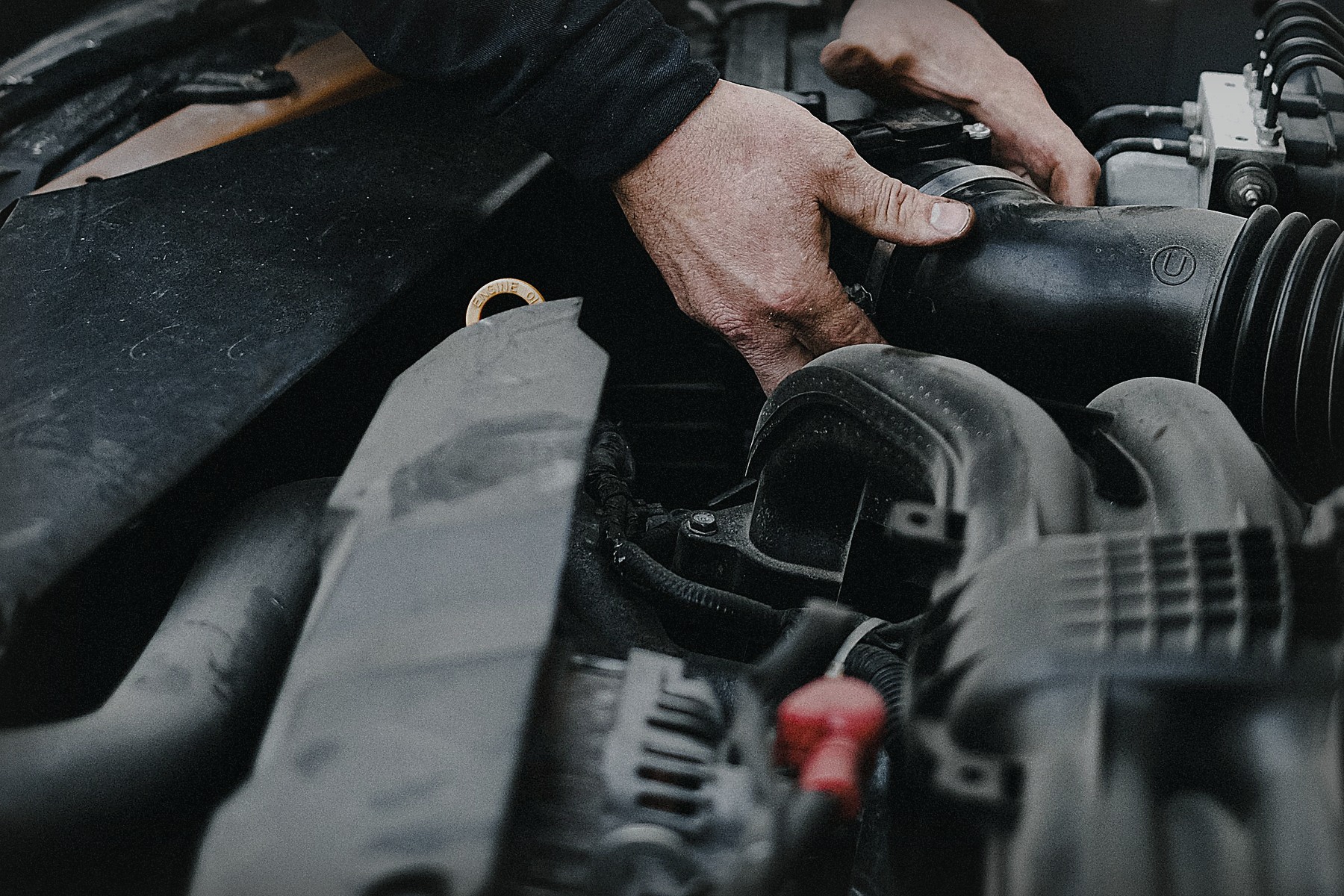 Mechanic working by hand inside a car engine bay