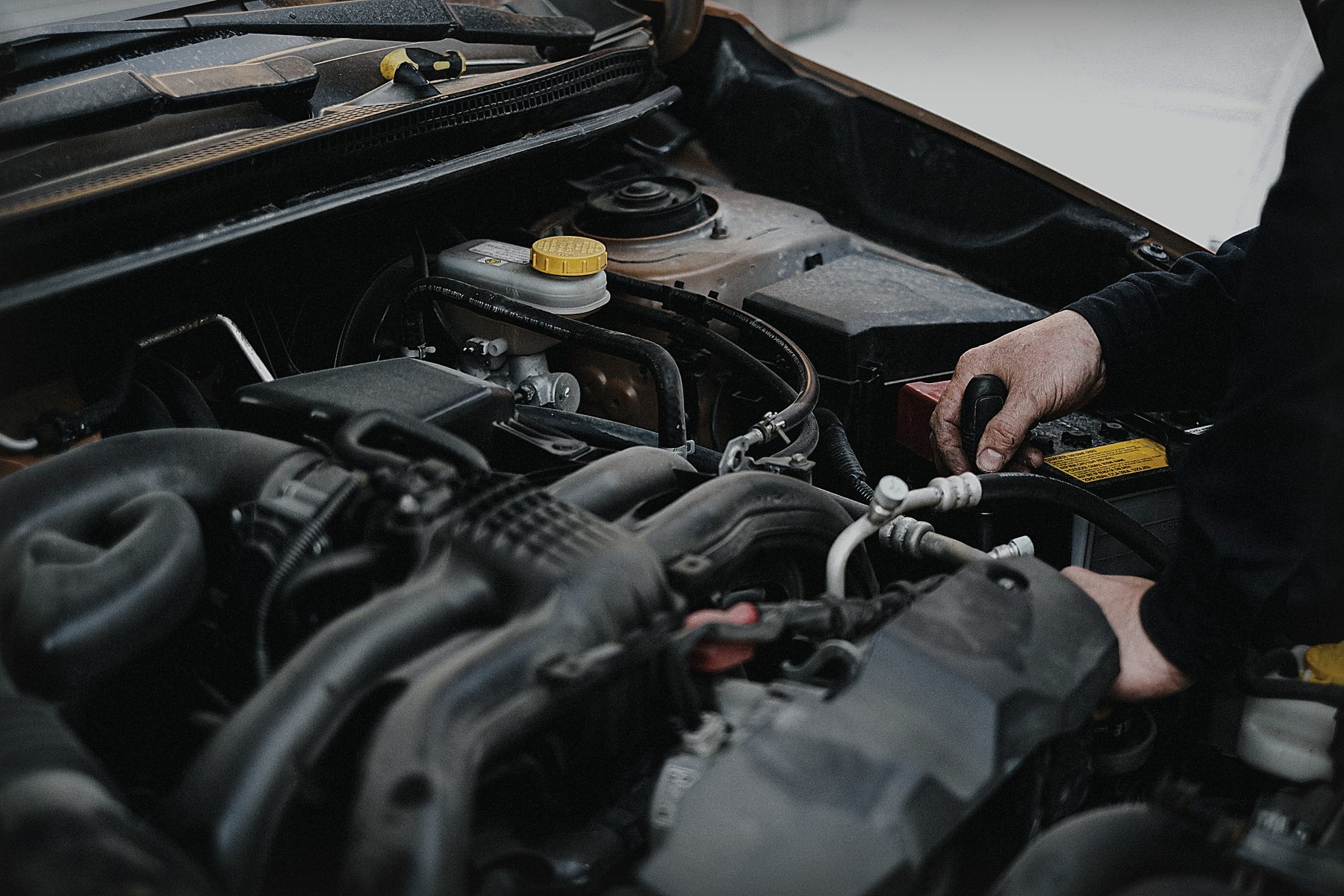 Mechanic inspecting components inside a car engine bay