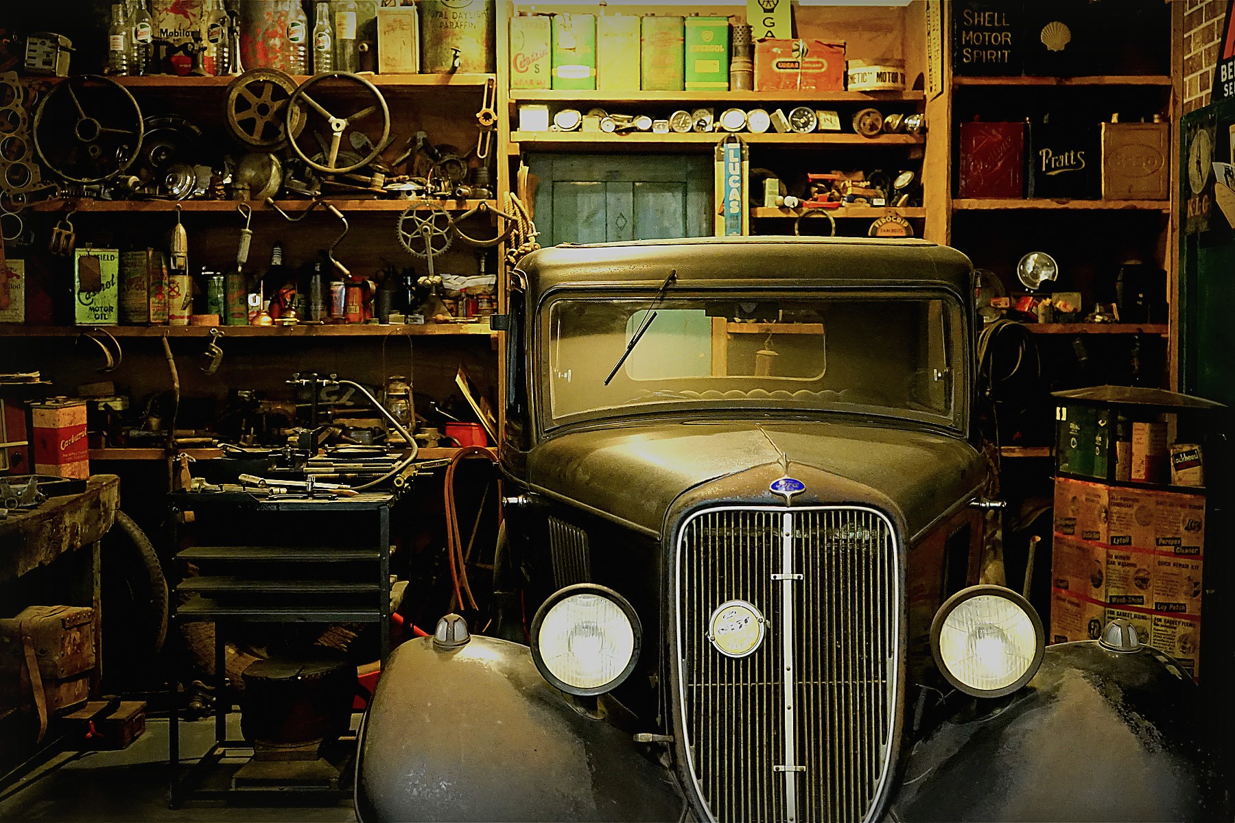 Vintage car surrounded by tools and parts inside an old garage